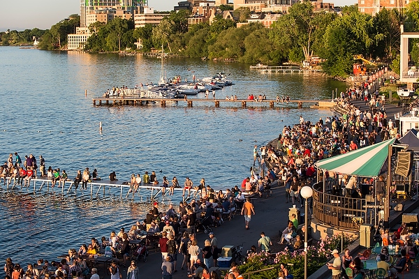 People relax along the swimming pier at the Memorial Union Terrace at the University of Wisconsin-Madison as the sun sets over Lake Mendota during a summer evening on June 21, 2014. In the background, boats are docked at the Goodspeed Family Pier. (Photo by Jeff Miller/UW-Madison)